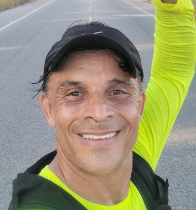 Foto de perfil de um atleta sorrindo, em traje esportivo, transmitindo alegria e entusiasmo pela prática esportiva.
