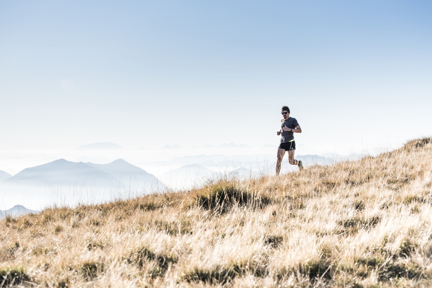 Atleta correndo em uma trilha ao ar livre, com uma montanha imponente e nuvens suavemente coberta no fundo, criando um cenário inspirador de natureza e desafio
